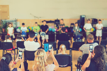 Children's holiday in elementary School. Children on stage perform in front of parents. image of...