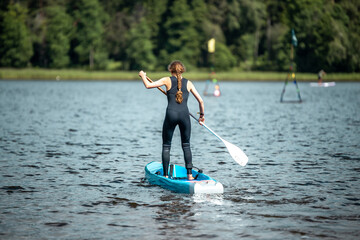 Closeup shot of a woman in a black sports suit paddling on a lake in sup competition