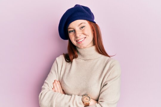 Young red head girl wearing french look with beret happy face smiling with crossed arms looking at the camera. positive person.