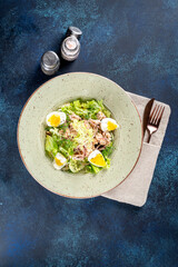 Salad with omul in a white plate on a blue background