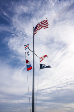 Flags on display against a blue sky with light clouds at Honeymoon Island in Florida