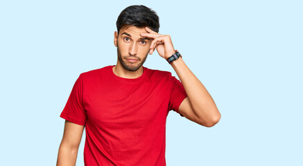 Fototapeta premium Young handsome man wearing casual red tshirt worried and stressed about a problem with hand on forehead, nervous and anxious for crisis