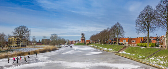 Fototapeta na wymiar Panorama of people skating at the historic windmill of Dokkum, Netherlands