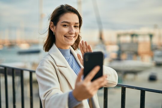 Young hispanic woman smiling happy doing video call using smartphone at the city.