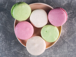 Colored macarons on a plate on gray background
