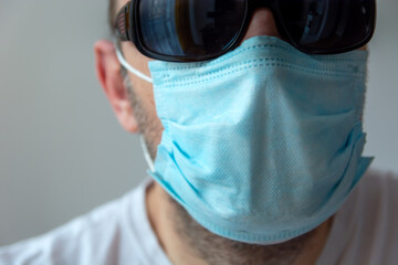 Male face in a blue surgical mask and sunglasses