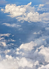 Fluffy sky clouds lit by afternoon sun, as seen from commercial airplane flying over