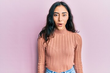 Obraz premium Hispanic teenager girl with dental braces wearing casual clothes scared and amazed with open mouth for surprise, disbelief face