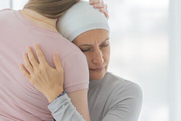 A middle-aged breast cancer woman hug and cuddle her daughter with sadness and fear for her sickness
