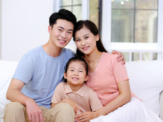 Obraz premium A happy family of three is sitting on the sofa in the living room
