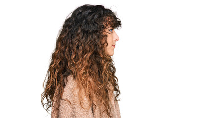 Young hispanic girl wearing winter clothes looking to side, relax profile pose with natural face with confident smile.