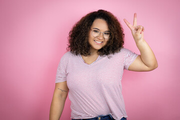 Young african american woman wearing red stripes t-shirt over pink background showing and pointing up with fingers number two while smiling confident and happy