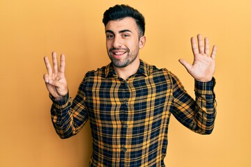 Young hispanic man wearing casual clothes showing and pointing up with fingers number eight while smiling confident and happy.
