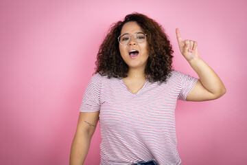 Young african american woman wearing red stripes t-shirt over pink background pointing finger up with successful idea. Exited and happy. Number one. - Powered by Adobe