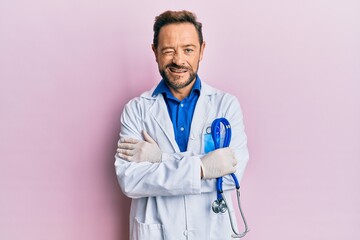 Middle age man wearing doctor uniform winking looking at the camera with sexy expression, cheerful...