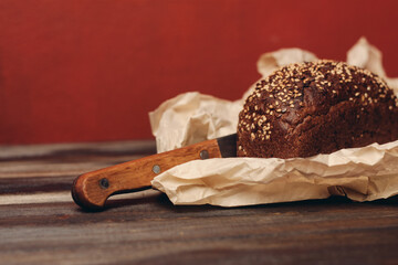 rye bread on a wooden table paper packaging sharp knife red background board