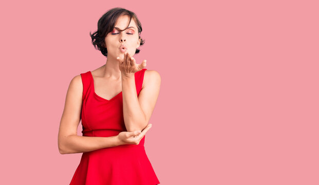 Beautiful young woman with short hair wearing casual style with sleeveless shirt looking at the camera blowing a kiss with hand on air being lovely and sexy. love expression.