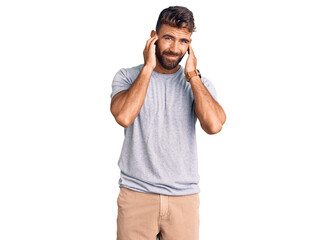 Young hispanic man wearing casual clothes covering ears with fingers with annoyed expression for the noise of loud music. deaf concept.