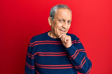 Senior hispanic man wearing casual clothes smiling looking confident at the camera with crossed arms and hand on chin. thinking positive.