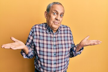Handsome senior man with grey hair wearing casual shirt clueless and confused expression with arms...