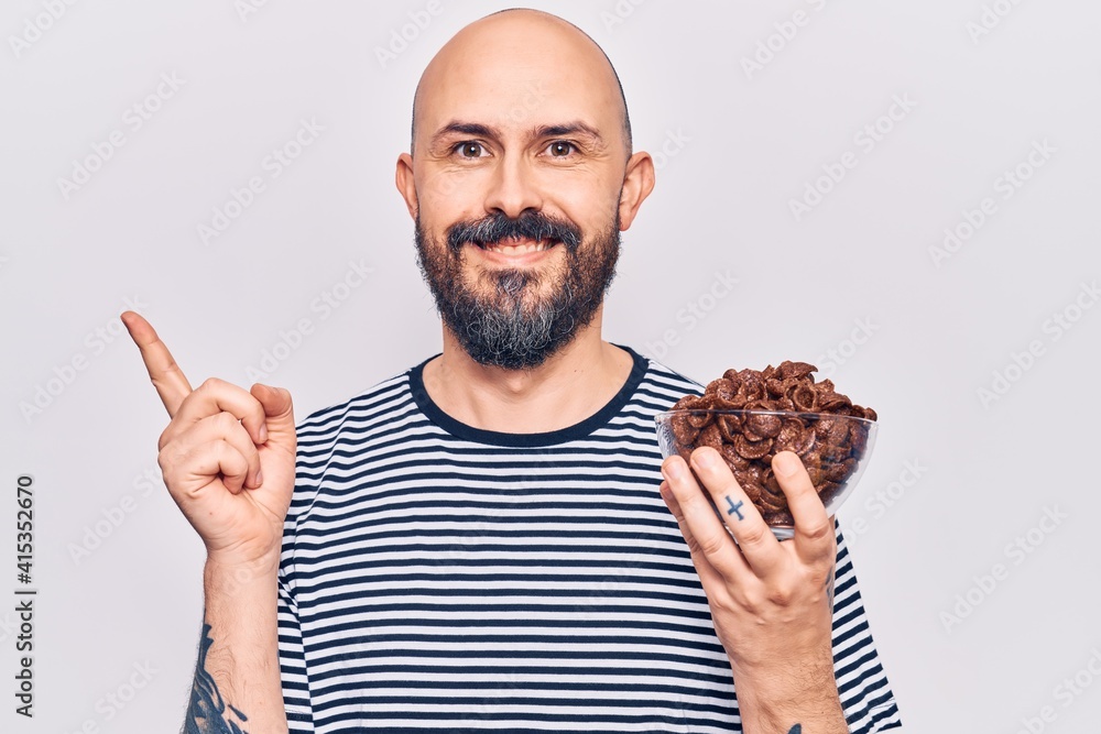 Poster Young handsome man holding chocolate cereals smiling happy pointing with hand and finger to the side