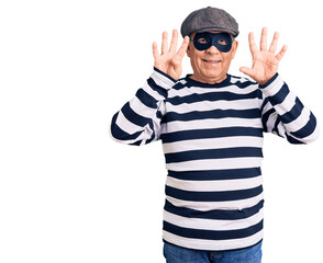 Senior handsome man wearing burglar mask and t-shirt showing and pointing up with fingers number nine while smiling confident and happy.