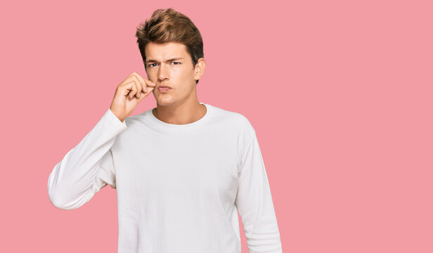 Handsome caucasian man wearing casual white sweater mouth and lips shut as zip with fingers. secret and silent, taboo talking