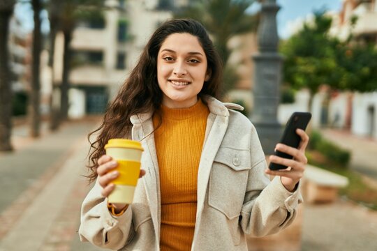 Young middle east woman using smartphone drinking coffee at the city.