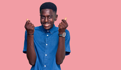Young african american man wearing casual clothes doing money gesture with hands, asking for salary...