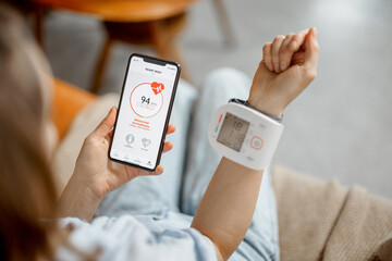 Woman measure heart rate and pressure with smart technology in phone while sitting on sofa at home....