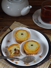 Putu belanda is Indonesian cookies which has vla filling, crashed peanut, and topping with raisin. Served in white plate on tray along with teapot and glass of tea. Concept on snacking or tea time. 