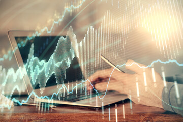 Double exposure of man's hands holding and using a digital device and forex graph drawing. Financial market concept.