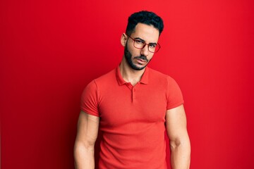 Young hispanic man wearing casual clothes and glasses skeptic and nervous, frowning upset because...