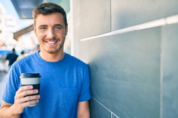 Young caucasian man using smartphone and drinking take away coffee at the city.