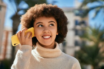 Young hispanic girl smiling happy listening audio message using smartphone at the city.