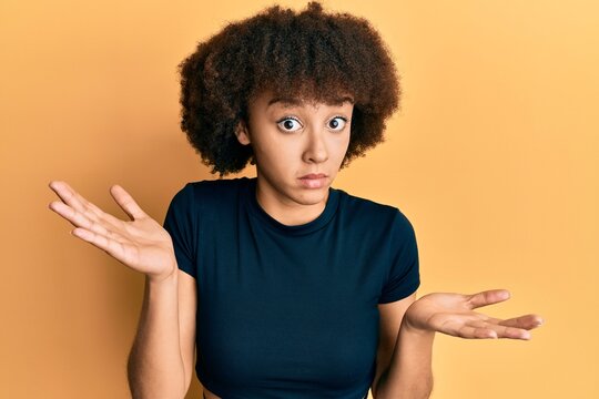 Young hispanic girl wearing casual clothes clueless and confused with open arms, no idea and doubtful face.