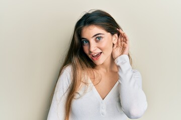 Fototapeta premium Young caucasian woman wearing casual white t shirt smiling with hand over ear listening and hearing to rumor or gossip. deafness concept.