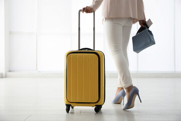 Businesswoman with yellow travel suitcase in airport