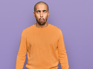Fototapeta premium Hispanic adult man wearing casual winter sweater making fish face with lips, crazy and comical gesture. funny expression.