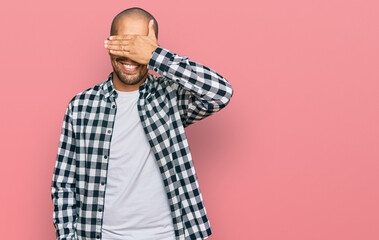 Hispanic adult man wearing casual clothes smiling and laughing with hand on face covering eyes for surprise. blind concept.