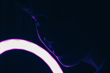 Glowing purple and blue flowers silhouette of the girl's face in the dark on the background of the 
cycle lamp light 