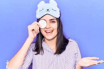 Young beautiful girl wearing funny sleep mask using makeup remover cotton celebrating achievement with happy smile and winner expression with raised hand