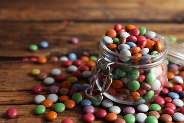 Delicious dragee in jar on wooden table, closeup. Space for text