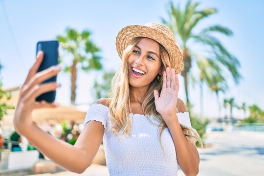 Young blonde tourist girl smiling happy doing video call using smartphone at the city.