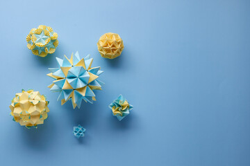 Set of multicolor handmade modular origami balls or Kusudama Isolated on blue background. Visual art, geometry, art of paper folding, paper crafts. Top view, close up, selective focus, copy space.