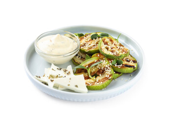 Delicious grilled zucchini slices served with sauce and cheese on white background