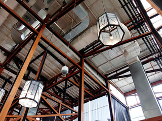 Obraz premium Construction of a large wooden roof and decorative lights. Wooden ceiling. Home and shopping Mall interior concept. Glass lantern hanging on wooden roof frames.