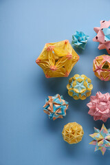 Set of multicolor handmade modular origami balls or Kusudama Isolated on blue background. Visual art, geometry, art of paper folding, paper crafts. Top view, close up, selective focus, copy space.