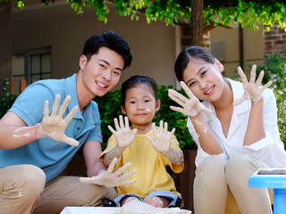 Happy family of three doing pottery together outdoors