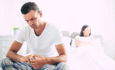 Fototapeta premium Young unhappy married couple in bedroom. Serious quarrel in family during covid-19 quarantine